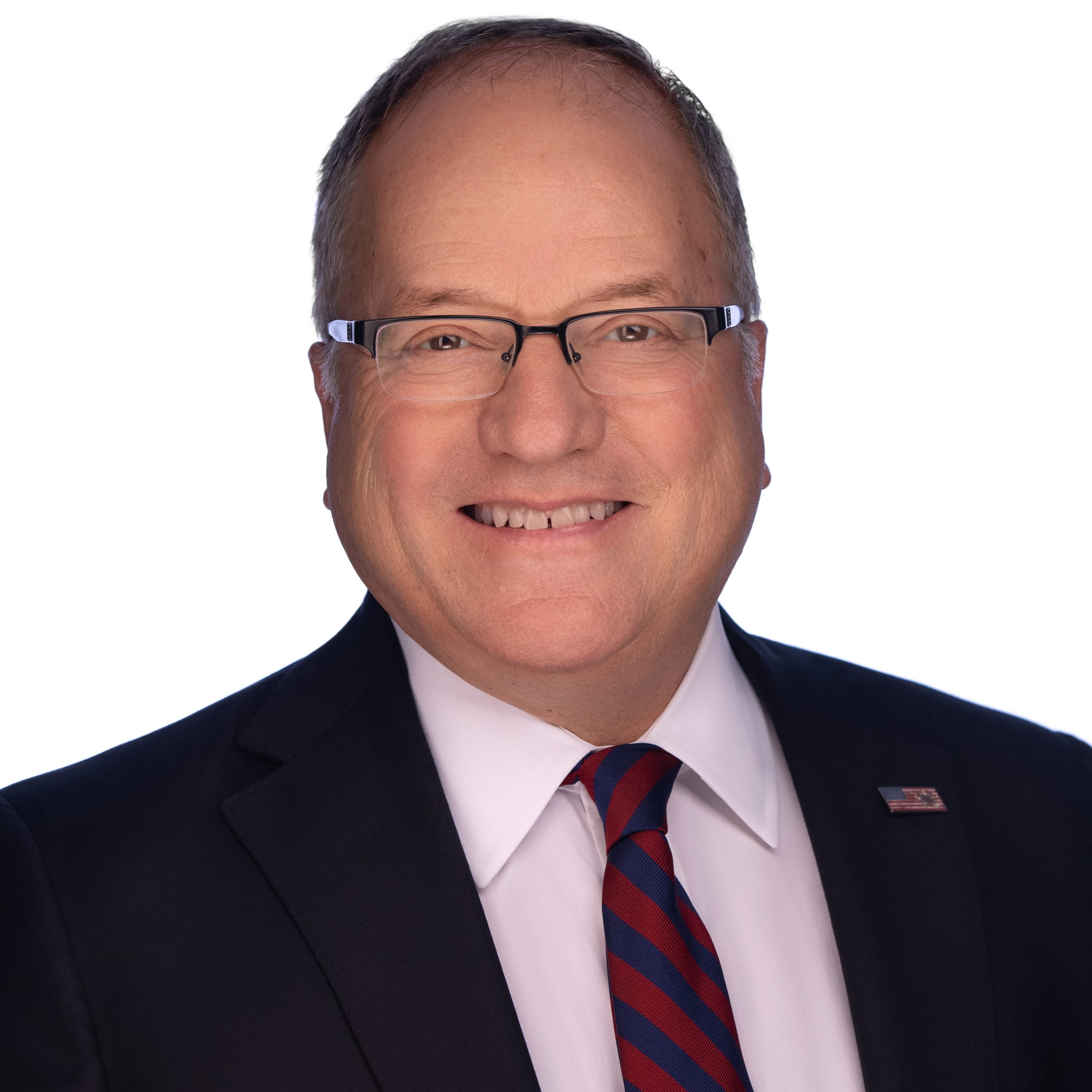 Professional headshot of smiling middle-aged man in suit